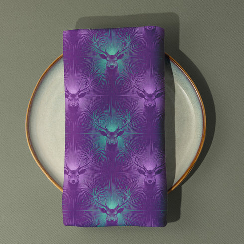 Set of four purple dining napkins featuring alternating teal and violet stag heads with radiating sunburst patterns, sized 18x18 inches.
